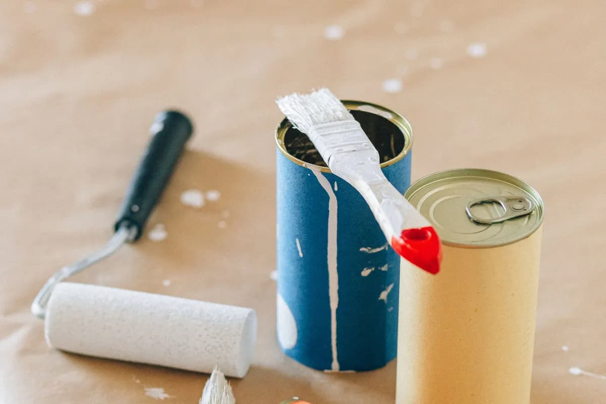 Leftover paint cans, a brush and a roller from a home DIY project.
