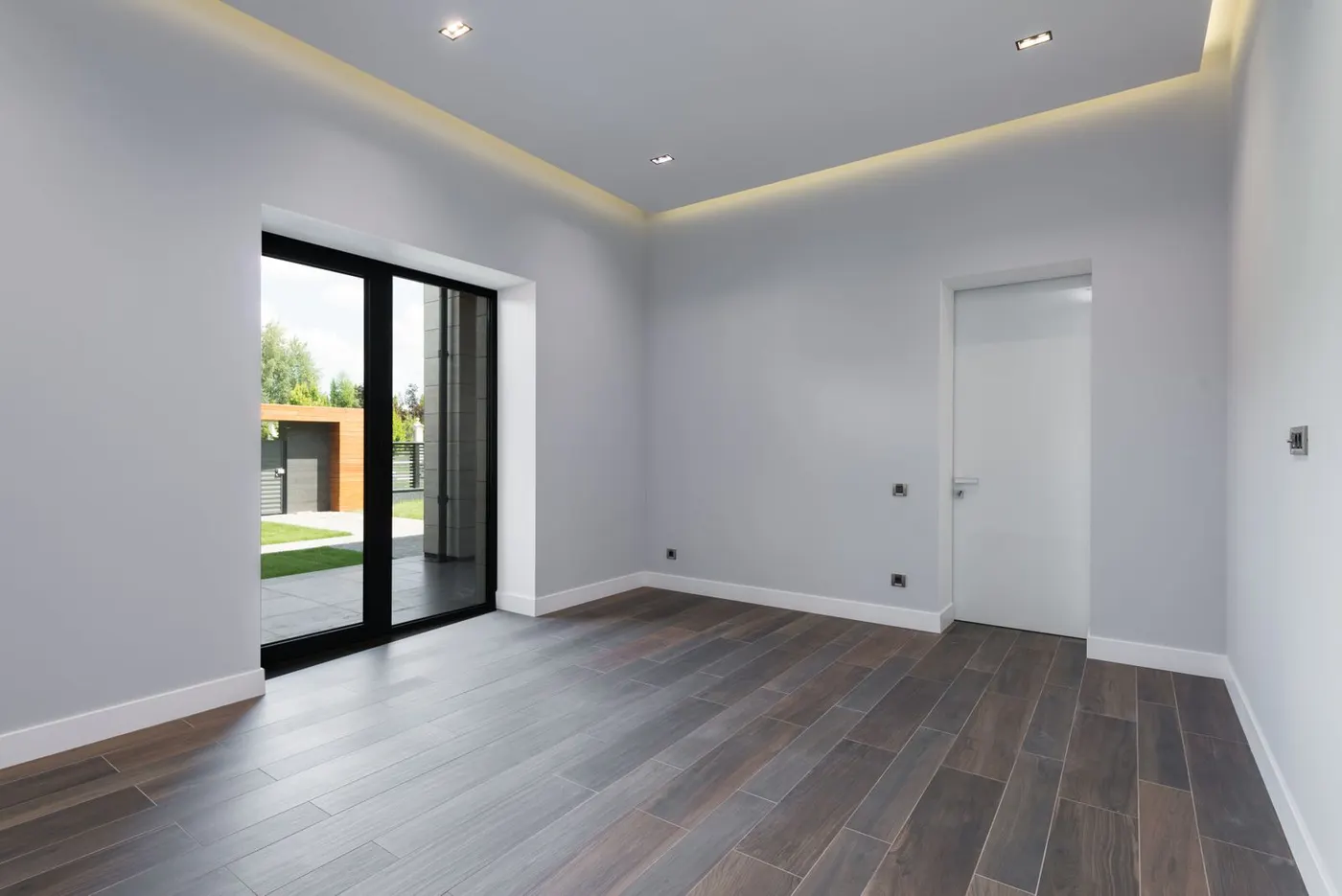 A tidy, empty hallway with a glass door and wooden flooring after a home has been cleared.