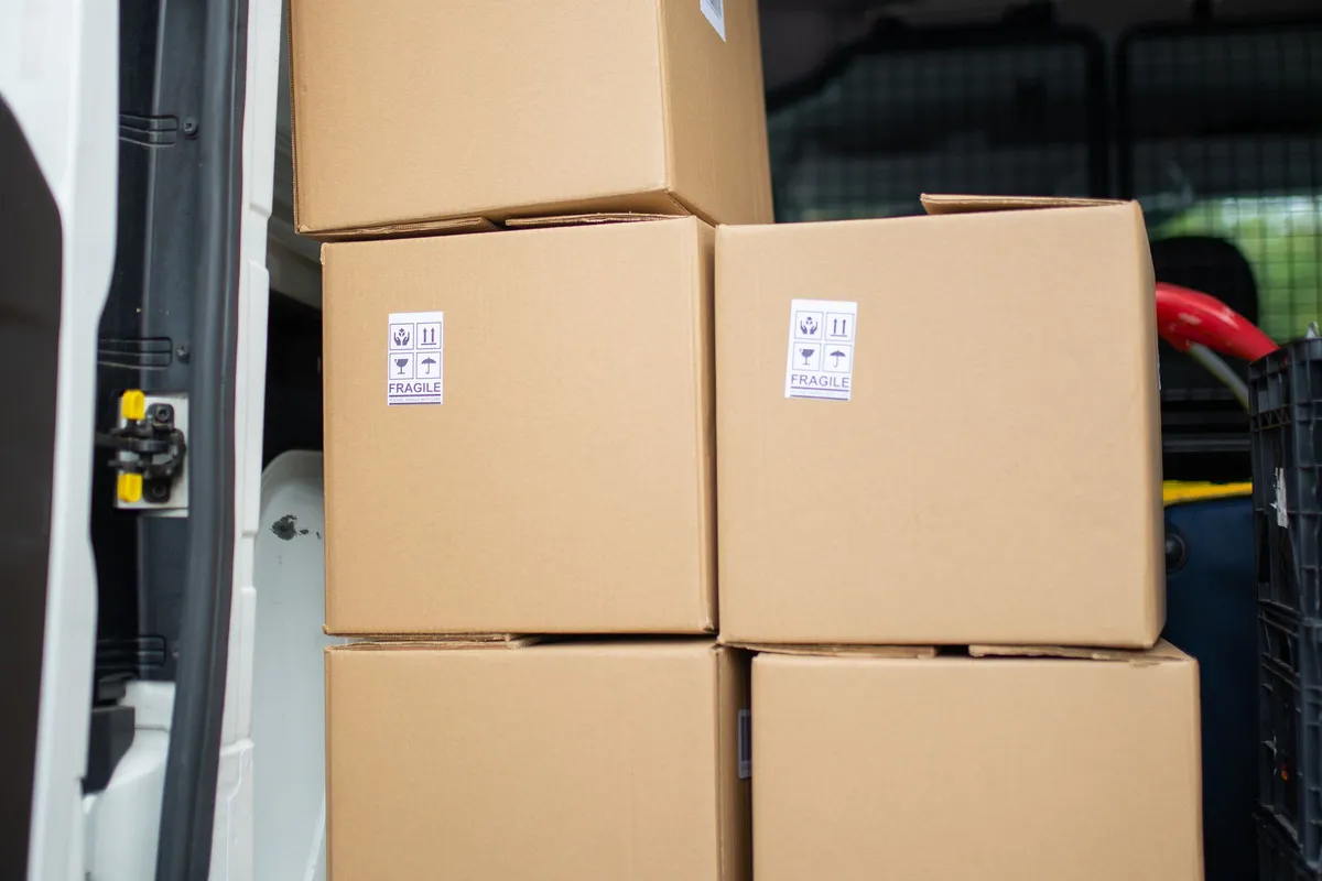 The open side door of a white van showing cardboard boxes stacked two high inside the cargo bay.