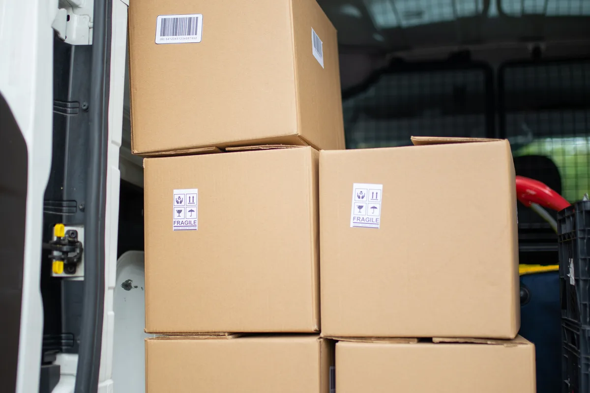 The open rear of a van packed tightly with stacked cardboard boxes.