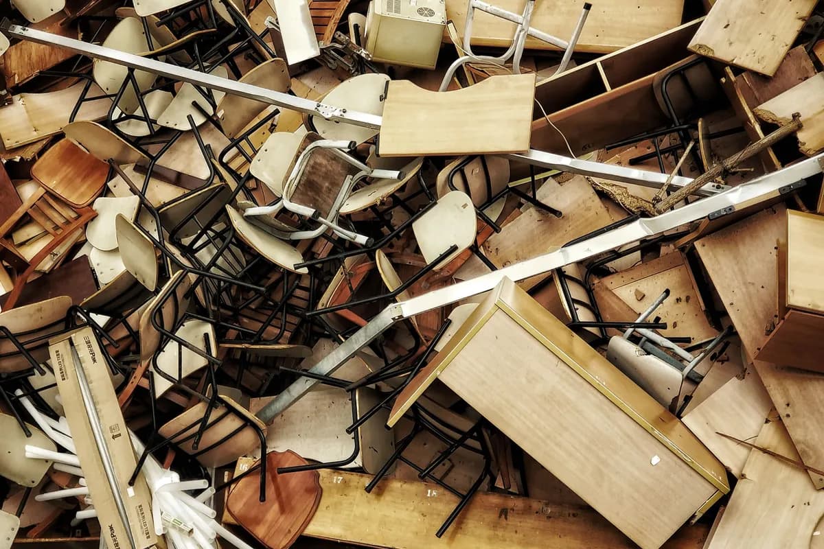 A dense pile of broken chairs, desks, shelving and timber panels stacked on top of each other, viewed from above.